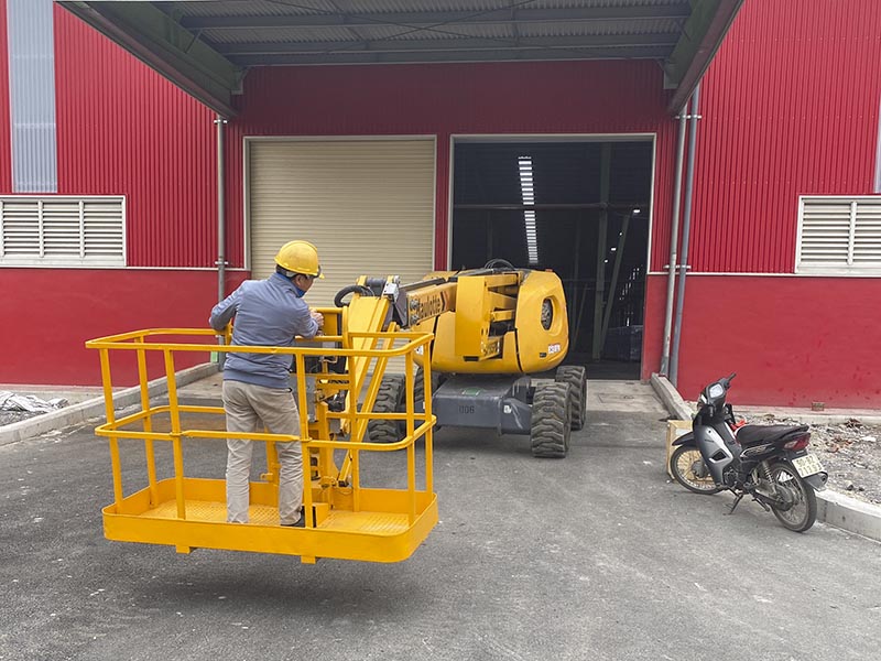 công nhân di chuyển xe nâng người Boom Lift vào trong nhà máy