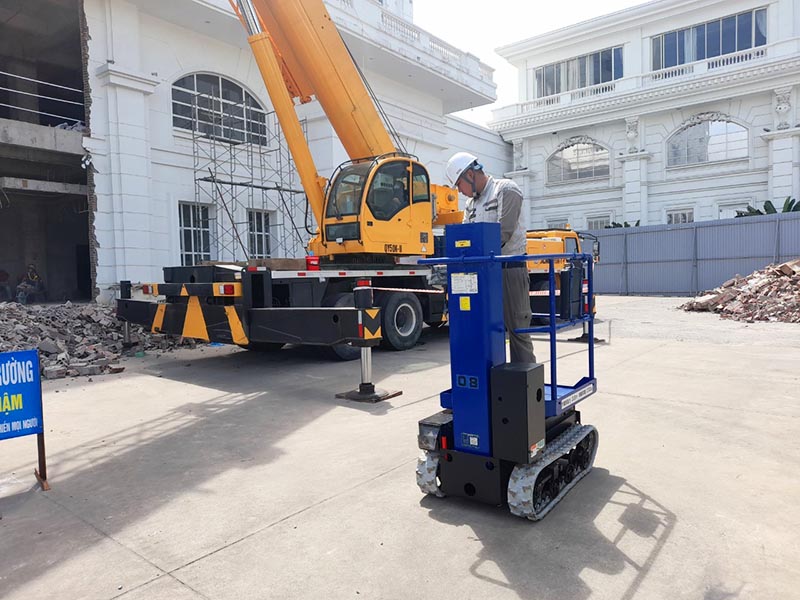 công nhân vận hành xe nâng người lên thẳng di chuyển trong công trường xây dựng