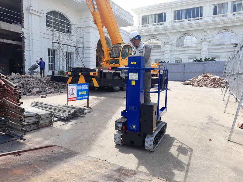 công nhân lái xe nâng người mini (Mast Lift) di chuyển trong công trường xây dựng