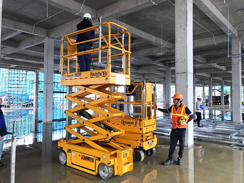 công nhân lái xe nâng người cắt kéo 8 mét làm việc vào công trường xây dựng