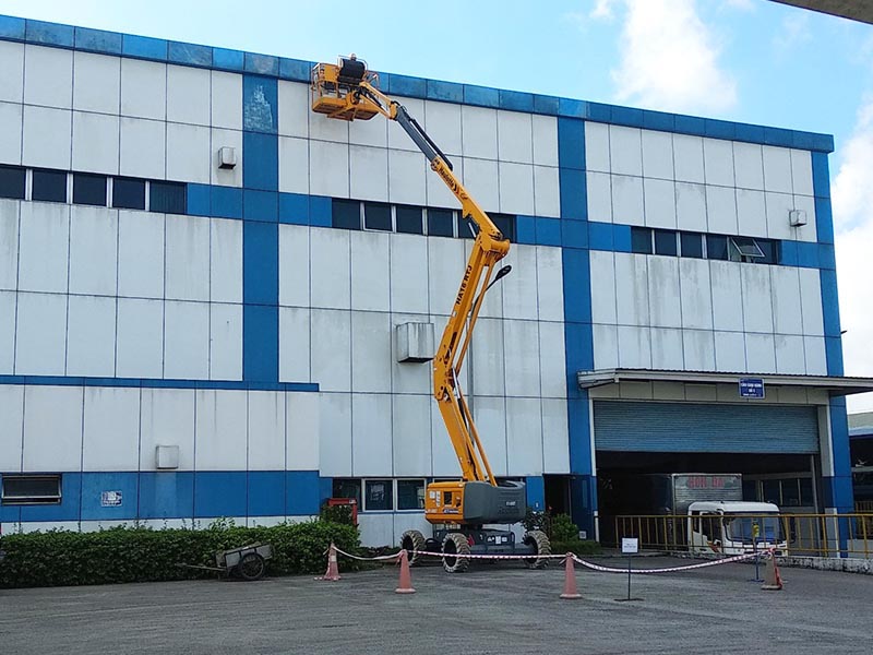 công nhân lái xe nâng người Boom Lift sơn sửa nhà máy