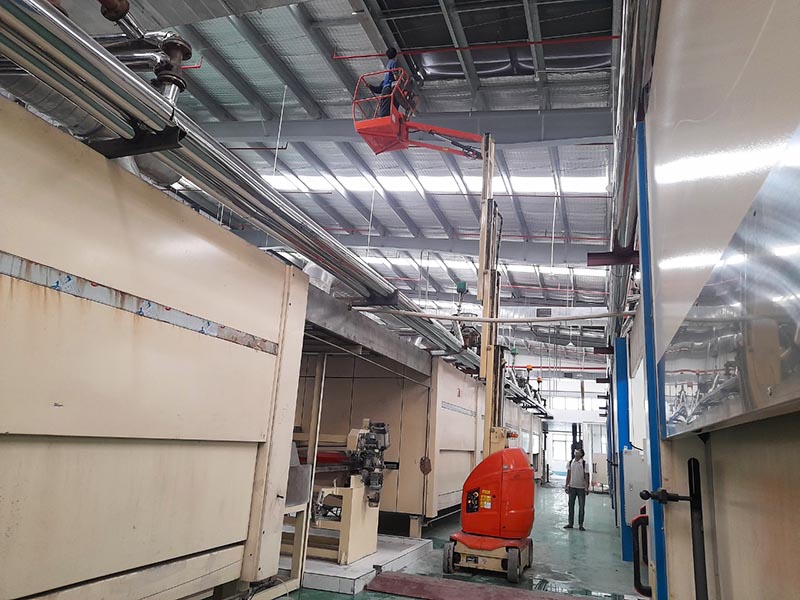 công nhân lái xe nâng người thi công trên trần nhà máy