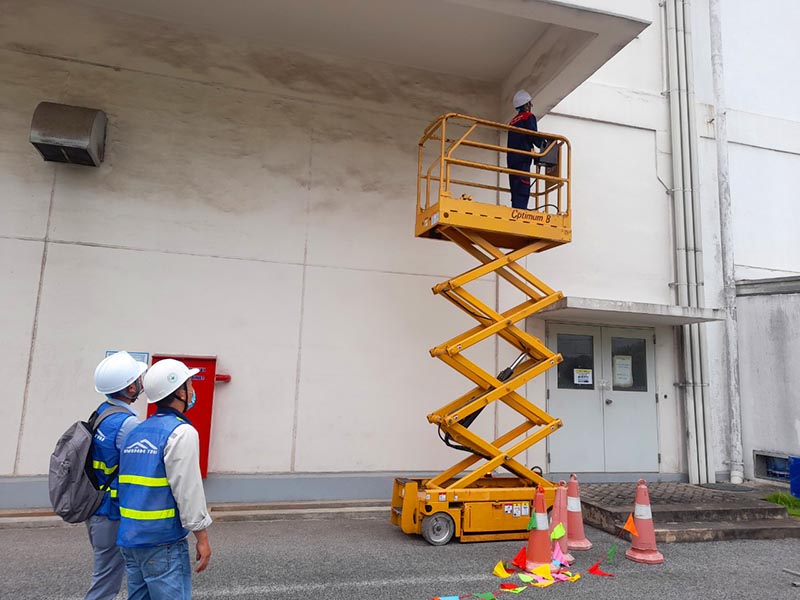 xe nâng người cắt kéo thi công sửa tòa nhà