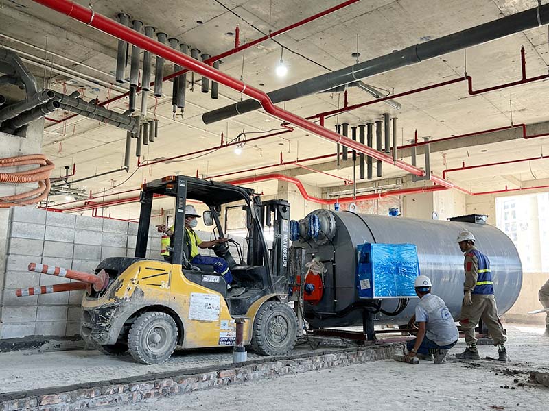 công nhân di chuyển nồi hơi công nghiệp bằng xe nâng hàng