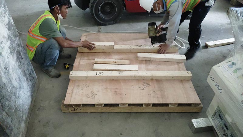 công nhân đóng chân đỡ hàng hoá trên pallet gỗ