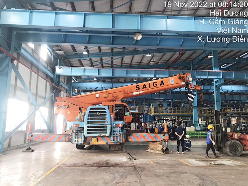 xe cẩu bánh lốp lắp đặt máy công nghiệp vào vị trí trong nhà máy