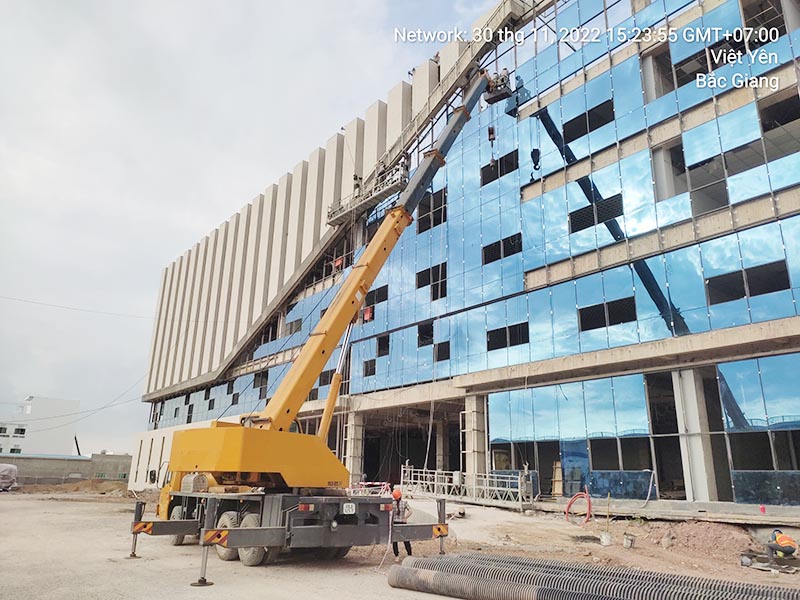 xe cẩu bánh lốp gắn giỏ nâng người thi công lắp kính chắn gió toà nhà