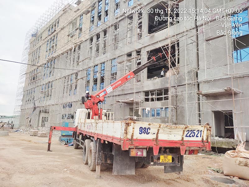 xe cẩu thùng cẩu vật liệu xây dựng lên tầng 2 của toà nhà