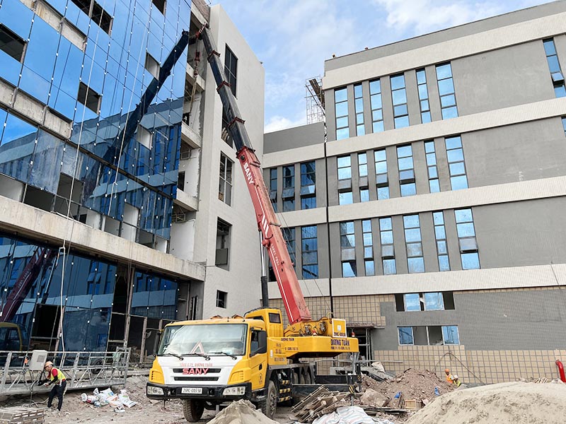 xe cẩu bánh lốp cẩu vật liệu xây dựng lên tầng cao của toà nhà