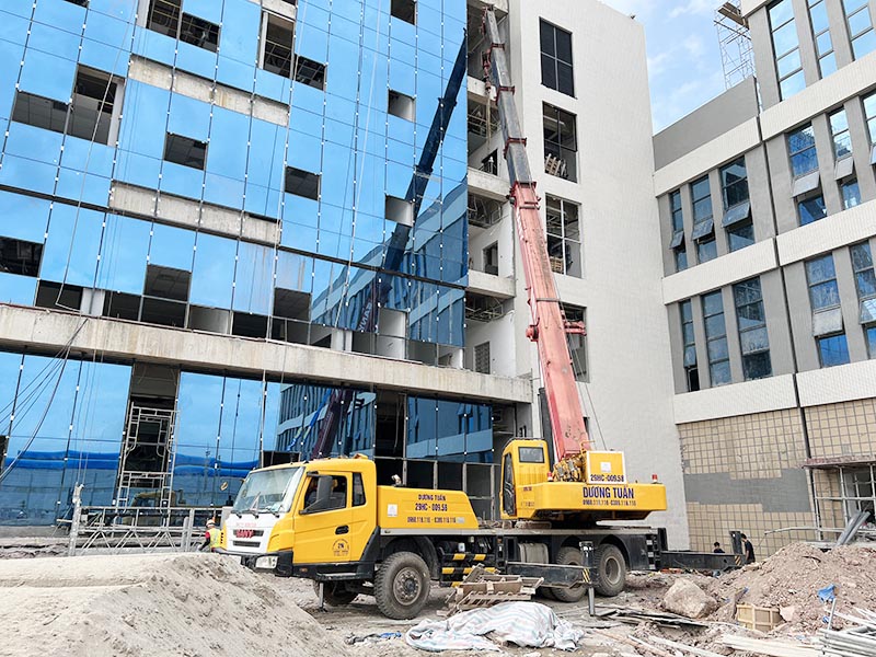 xe cẩu bánh lốp cẩu vật tư xây dựng lên vị trí cao của toà nhà