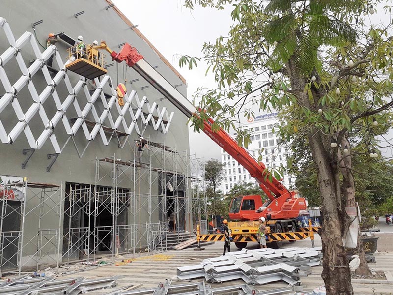 công nhân điều khiển xe cẩu gắn giỏ làm việc trên vị trí cao của toà nhà