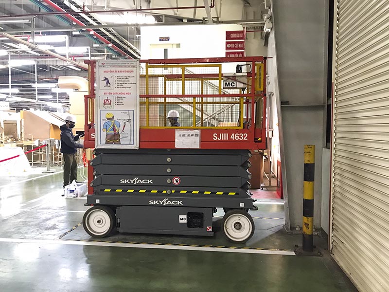 xe nâng người cắt kéo SkyJack làm việc bên trong nhà máy