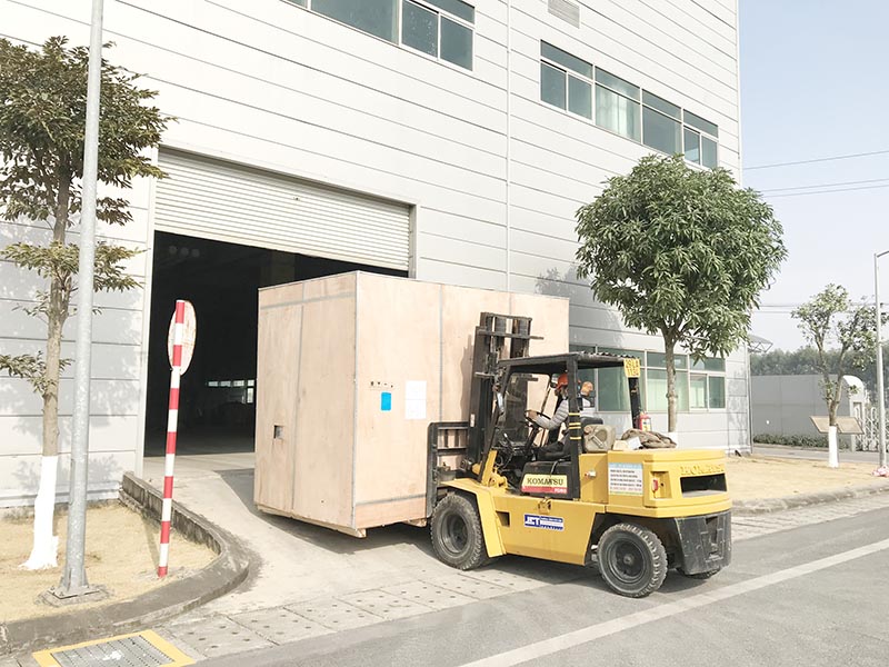 công nhân điều khiể xe nâng hàng di chuyển máy móc vào trong nhà máy