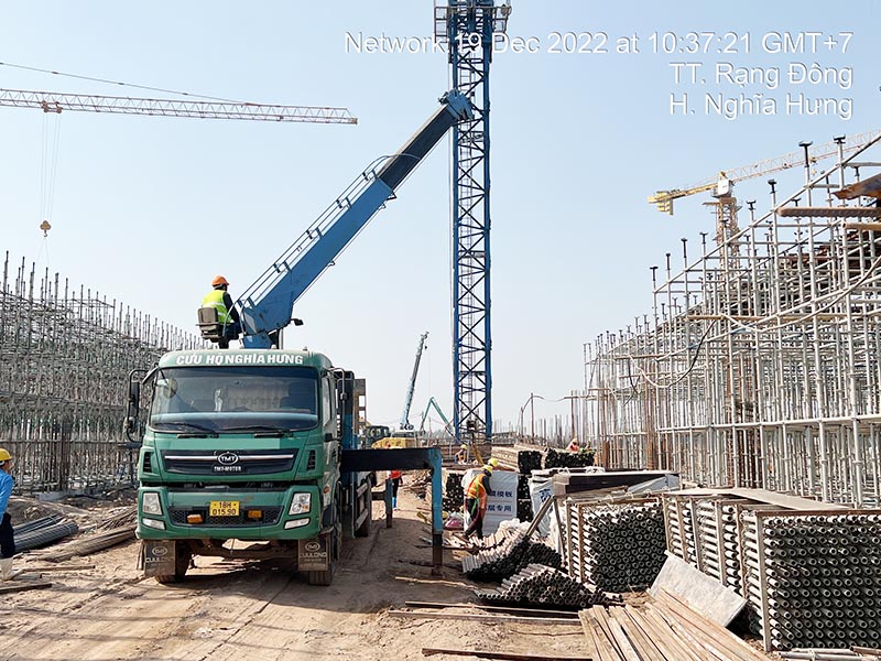 công nhân vận hành xe cẩu thùng cẩu vật liệu xây dựng tại công trường