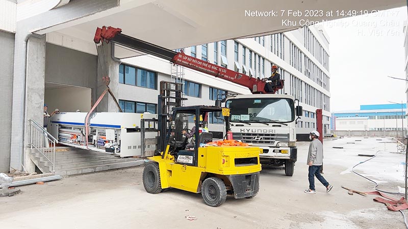 công nhân di chuyển máy công nghiệp hạng nặng bằng xe cẩu tự hành và xe nâng hàng