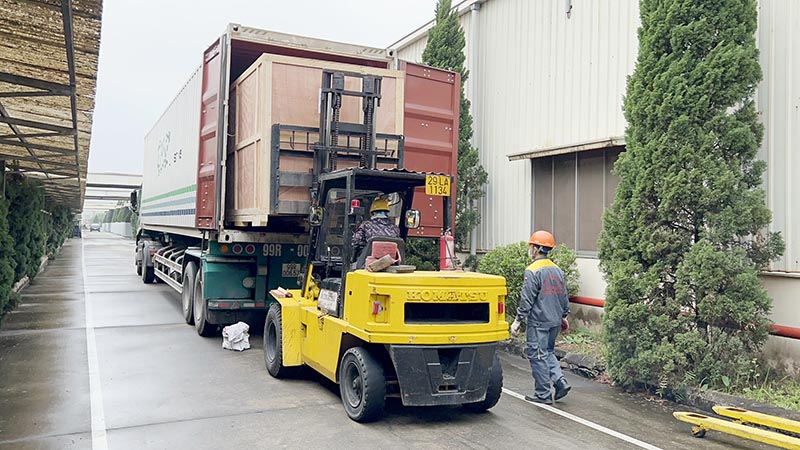 công nhân lái xe nâng hàng hạ kiện hàng từ xe container