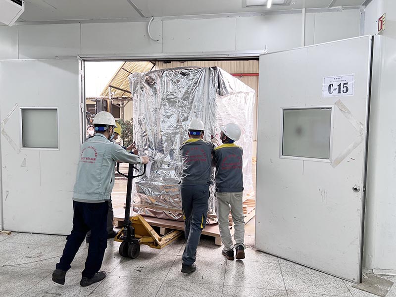 công nhân sử dụng xe nâng tay di chuyển máy công nghiệp vào trong nhà máy