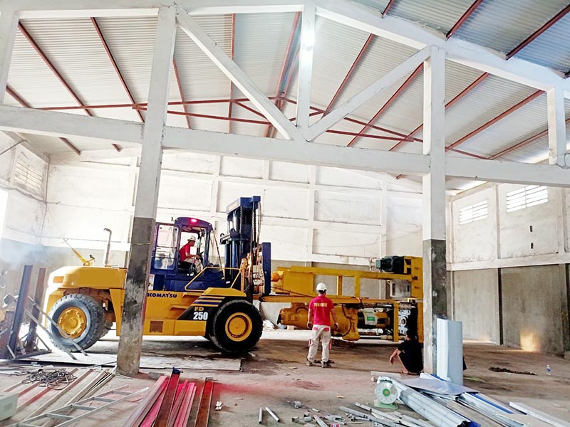 công nhân vận hành xe nâng hàng 25 tấn Komatsu di chuyển máy công nghiệp vào vị trí