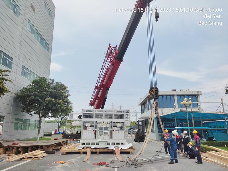 công nhân chuẩn bị dây cáp để cẩu thiết bị công nghiệp lên cao
