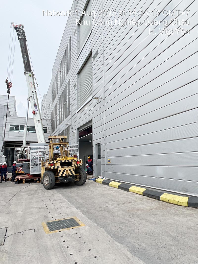 xe cẩu bánh lốp lắp đặt máy công nghiệp vào vị trí của nhà máy