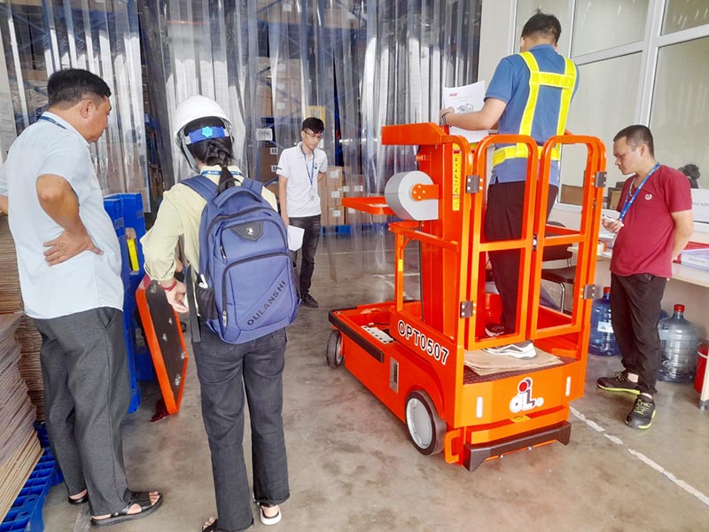 công nhân lái xe nâng người mini di chuyển bên trong kho hàng
