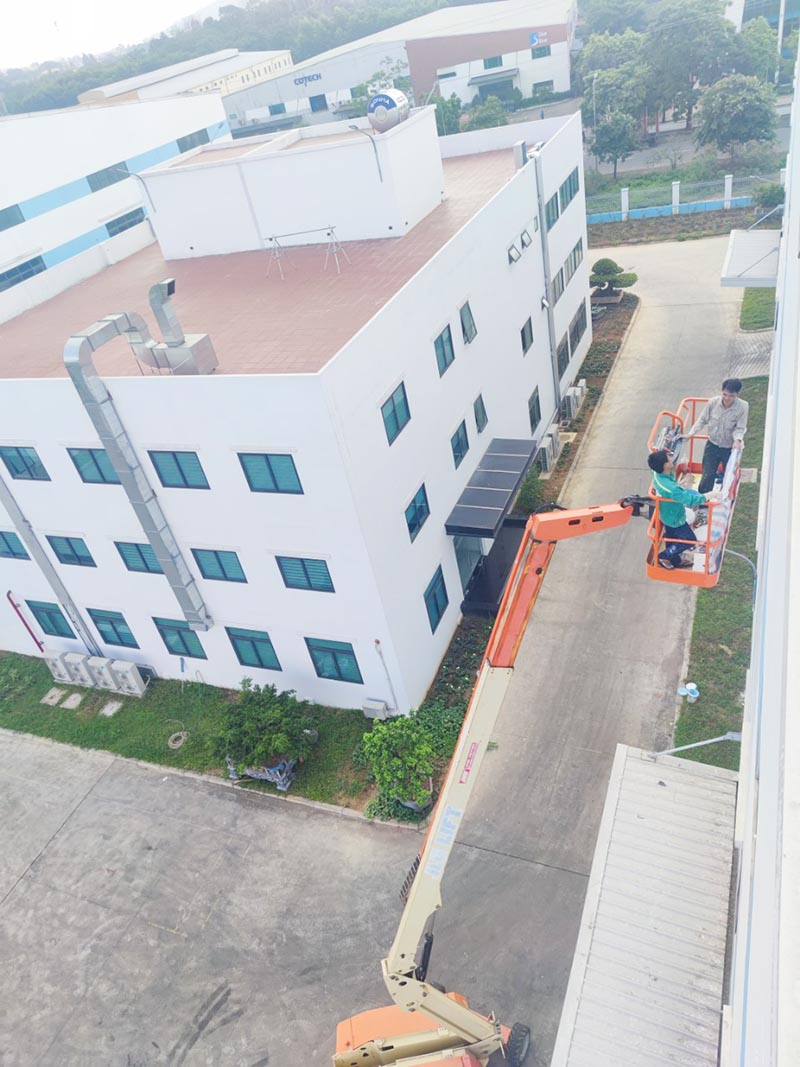 công nhân lái xe nâng người boomlift thi công sơn toà nhà