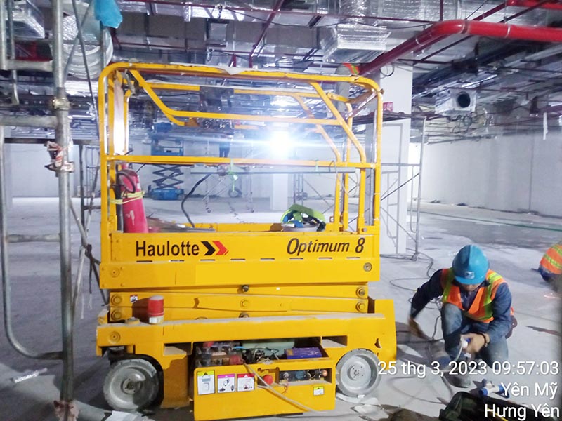công nhân sạc điện cho xe nâng người cắt kéo 8m làm việc Haulotte model Optimum 8