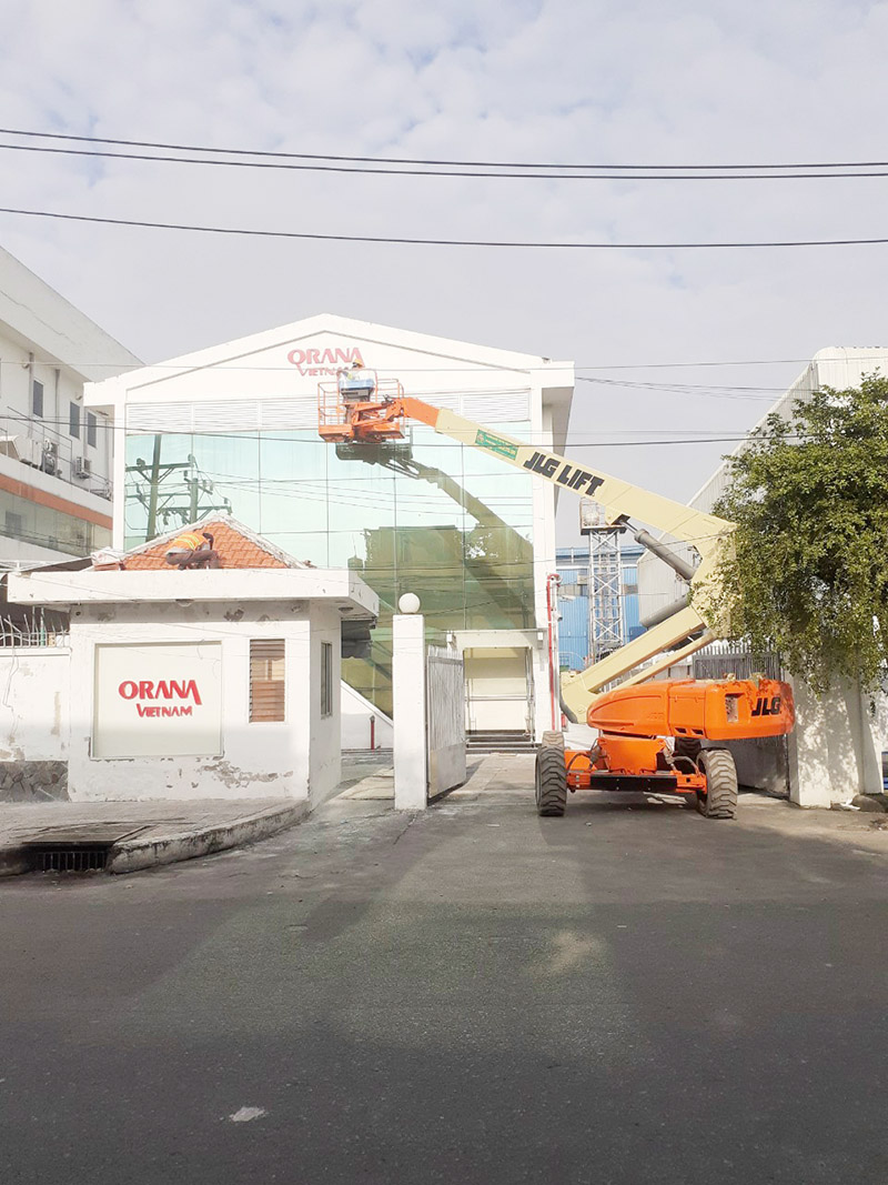 công nhân lái xe nâng người boomlift sơn lại logo nhà máy
