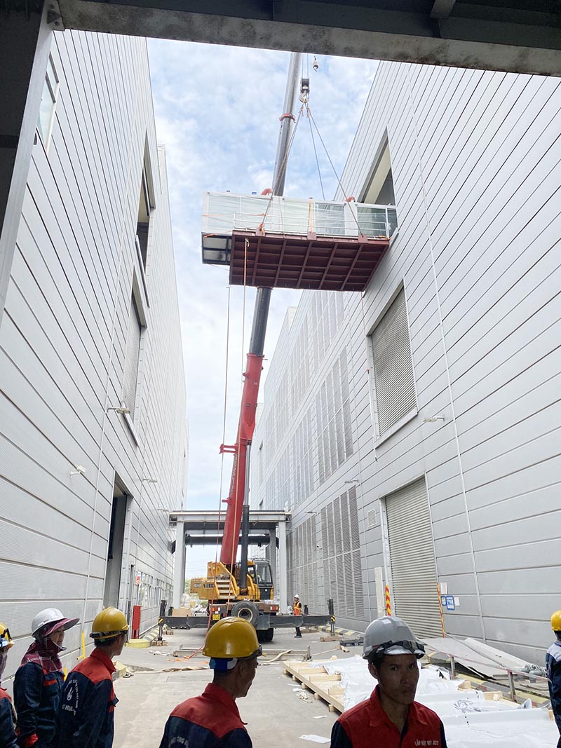 xe cẩu bánh lốp thực hiện nâng máy công nghiệp lên tầng 3 của nhà máy