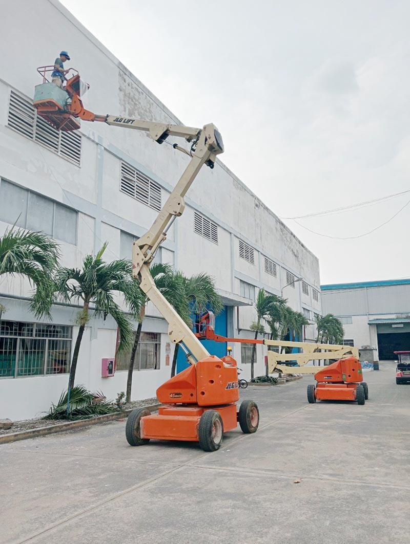 công nhân vận hành xe nâng người boomlift làm việc ngoài nhà máy